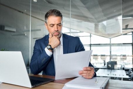 Serious and busy mid aged professional businessman wearing suit holding federal target letter
