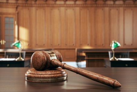 In an empty courtroom, a gavel sits on the judge's desk.