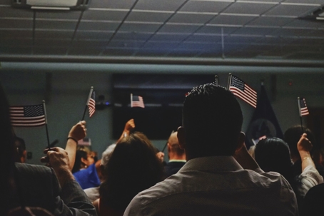 People holding American flags after passing their immigration test.